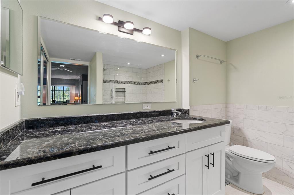 14770 Eagle Ridge Drive, Unit 112 Fort Myers, FL 33912 - Photo 12 of 32 a bathroom with a granite countertop sink a toilet and mirror