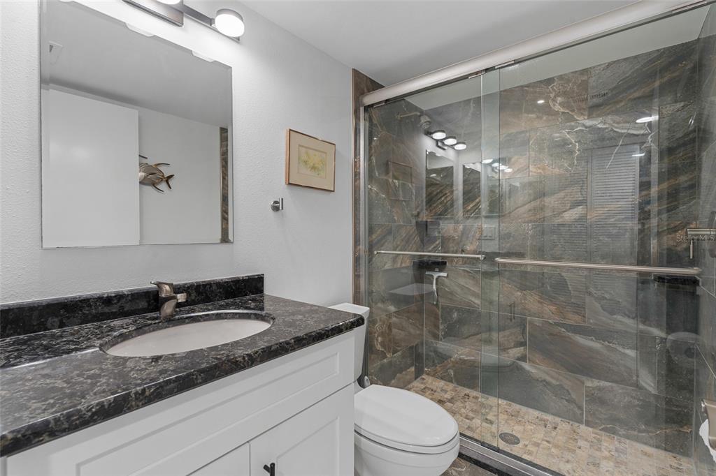14770 Eagle Ridge Drive, Unit 112 Fort Myers, FL 33912 - Photo 17 of 32 a bathroom with a granite countertop sink a mirror and a shower