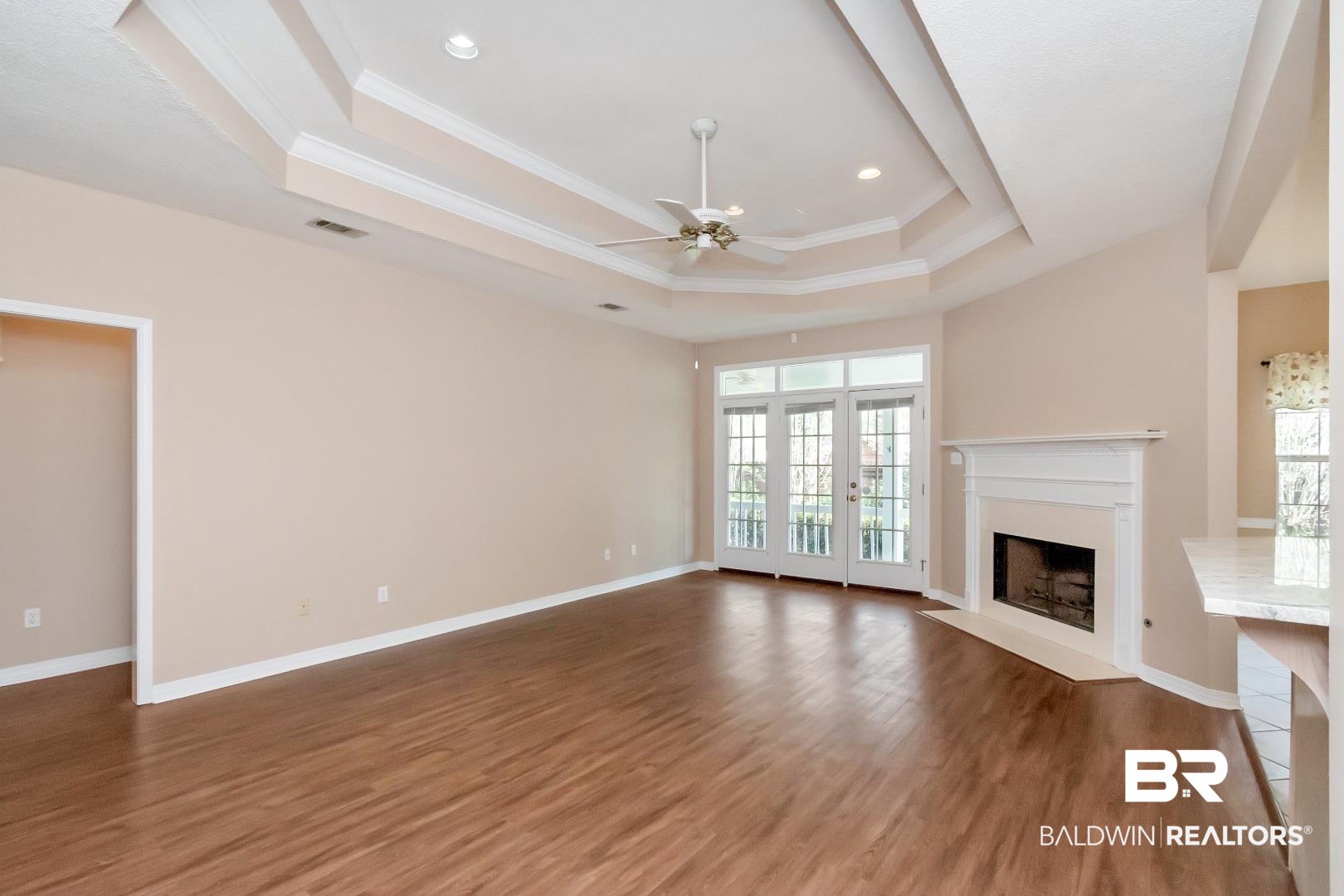 6117 Lennox Place Mobile, AL 36693 - Photo 9 of 39 Unfurnished living room with visible vents, ornamental molding, wood finished floors, a fireplace, and a tray ceiling