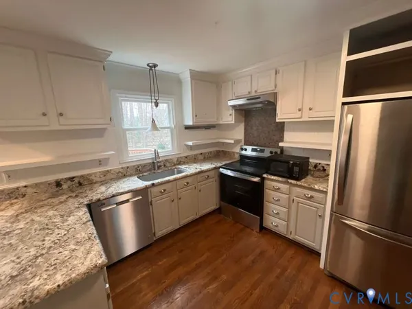 a kitchen with granite countertop stainless steel appliances a sink refrigerator and microwave