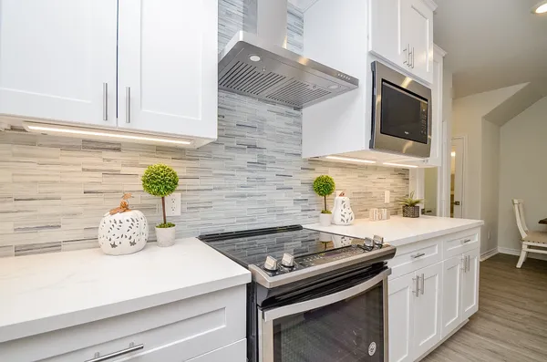 a kitchen with a stove and a white wooden cabinets