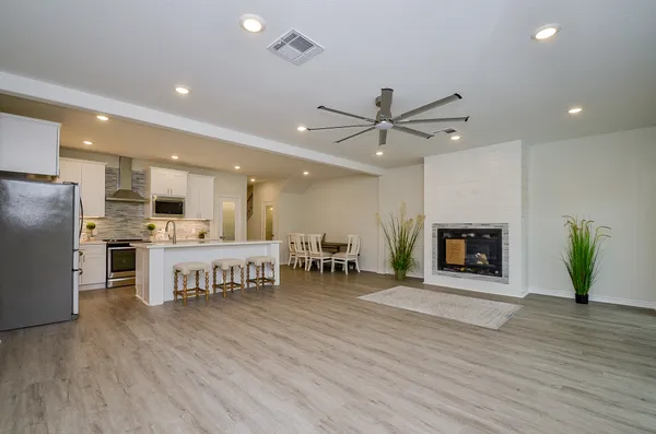 a view of a kitchen with furniture a ceiling fan and wooden floor