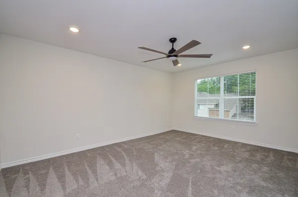 an empty room with a window and a fan