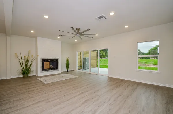 an empty room with windows fireplace and wooden floor