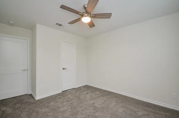 an empty room with a chandelier fan and windows