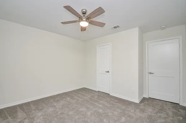 an empty room with a fan & a window