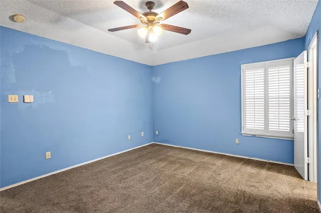 an empty room with a window and a fan