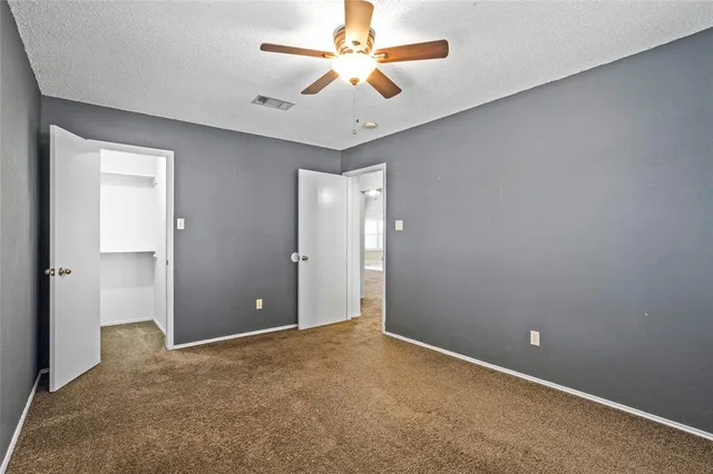 a view of an empty room and chandelier fan