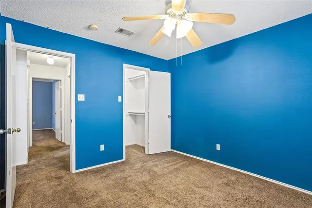 an empty room with closet and a chandelier fan