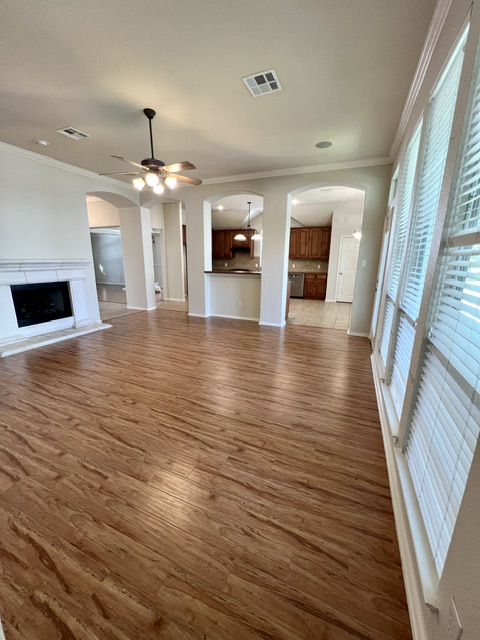 20724 Kearney Hill Road Pflugerville, TX 78660 - Photo 22 of 40 Spacious living area featuring wood-finish flooring, a white mantel fireplace, and a ceiling fan with integrated lighting