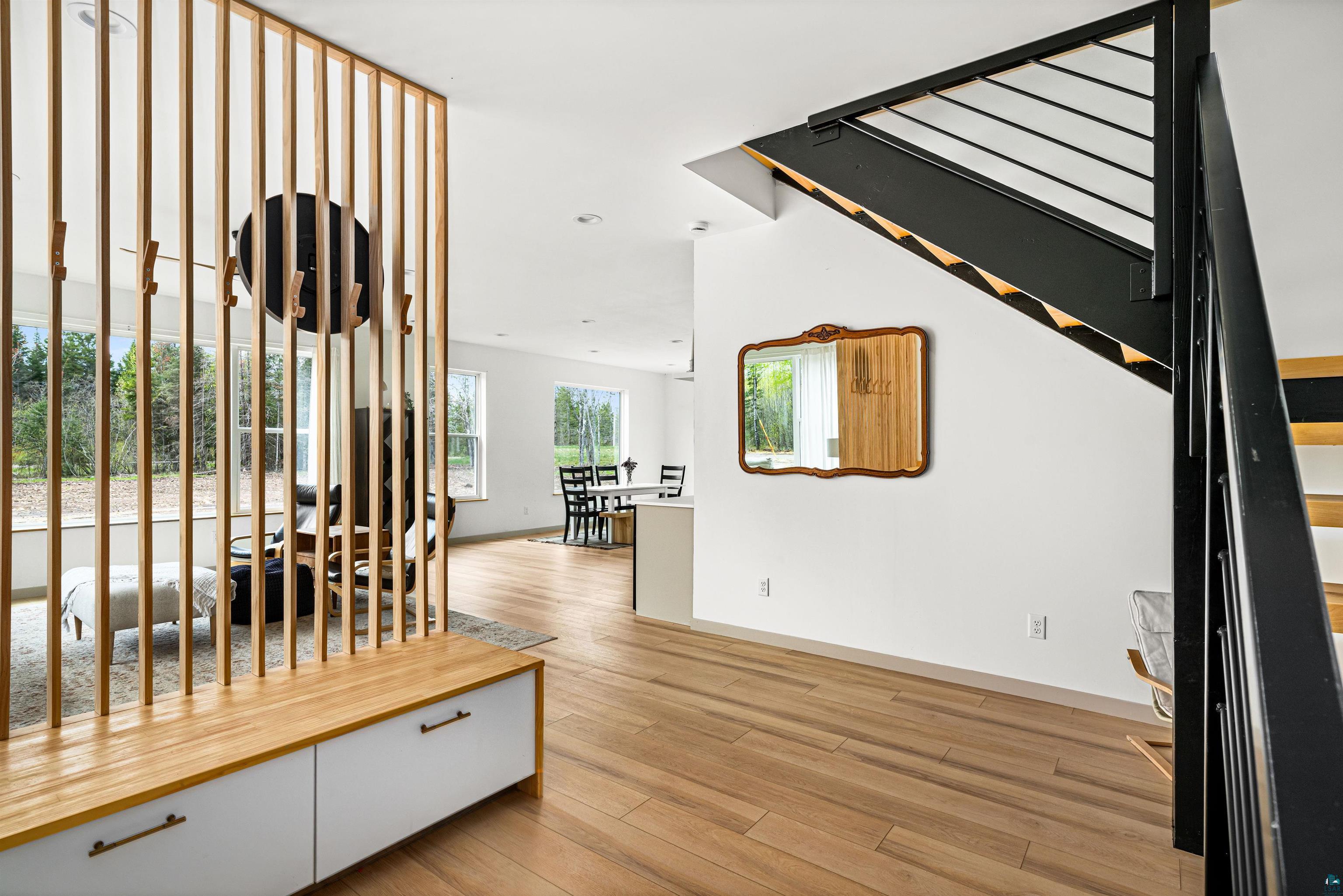 1825 East Shilhon Road Duluth, MN 55804 - Photo 9 of 37 Open concept interior featuring light vinyl plank style flooring, a contemporary slatted wood partition with integrated storage, and a modern staircase with a black metal railing