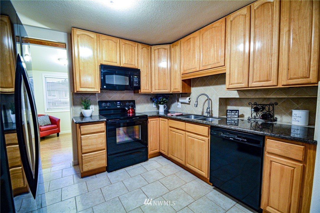 23920 Brier Road Brier, WA 98036 - Photo 4 of 23 a kitchen with stainless steel appliances granite countertop a stove top oven a sink dishwasher and a refrigerator with wooden cabinets