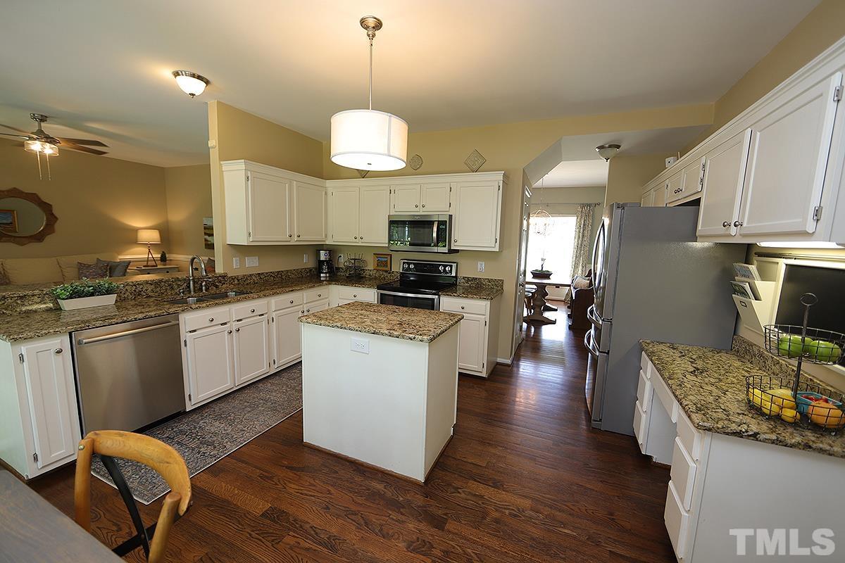 5152 Fairmead Circle Raleigh, NC 27613 - Photo 9 of 25 a kitchen with a center island wooden floor stainless steel appliances and cabinets