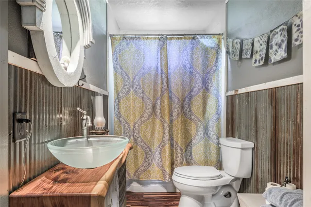 a bathroom with a sink a toilet a mirror and shower curtain