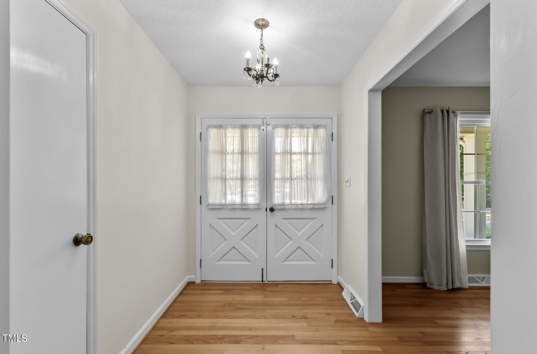 6401 Wrenwood Avenue Raleigh, NC 27607 - Photo 4 of 32 a view of an entryway with wooden floor and a chandelier