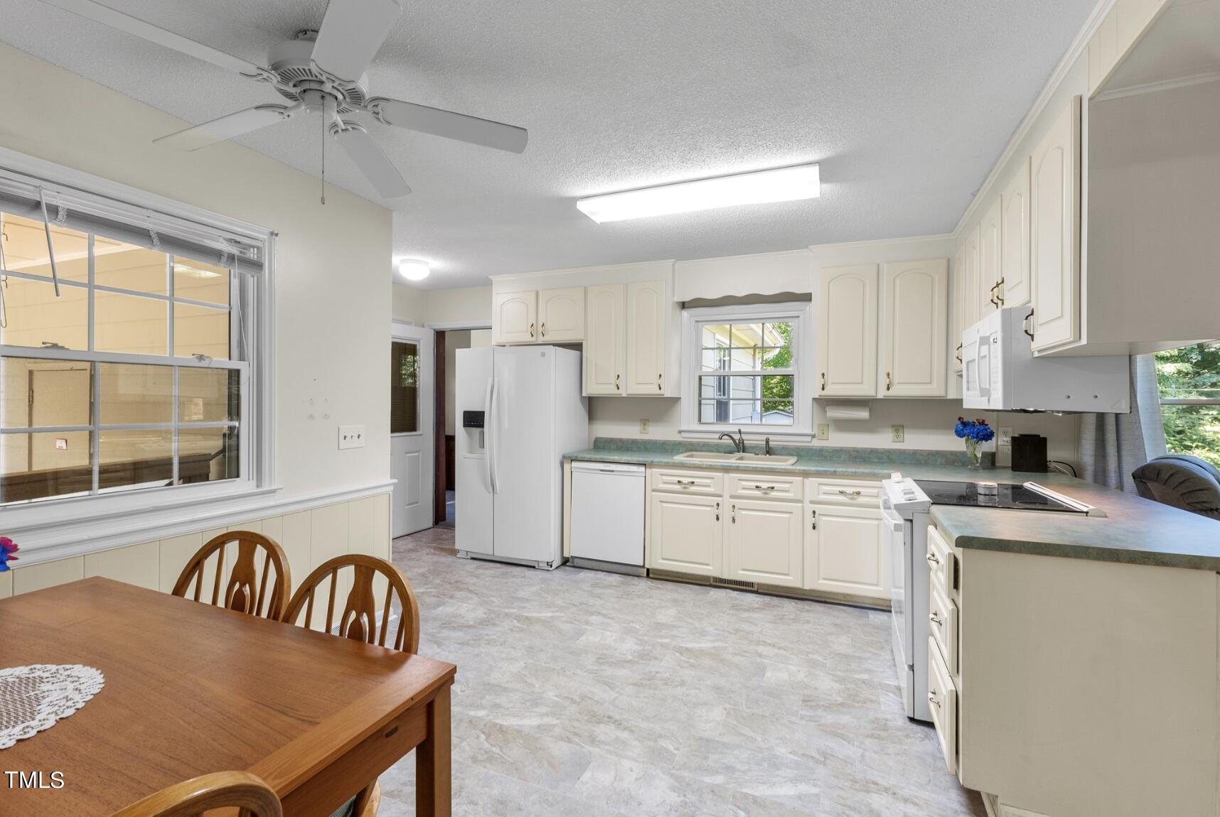 6401 Wrenwood Avenue Raleigh, NC 27607 - Photo 9 of 32 a kitchen with refrigerator cabinets dining table and chairs