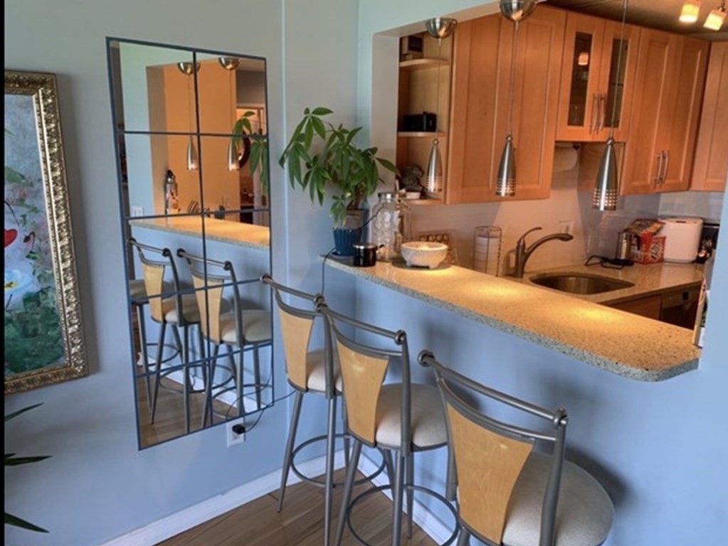 133 Commander Shea Boulevard, Unit 711 Quincy, MA 02171 - Photo 12 of 21 a kitchen with a table chairs refrigerator and sink