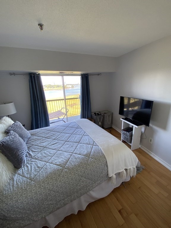 133 Commander Shea Boulevard, Unit 711 Quincy, MA 02171 - Photo 19 of 21 a bedroom with a bed and wooden floor