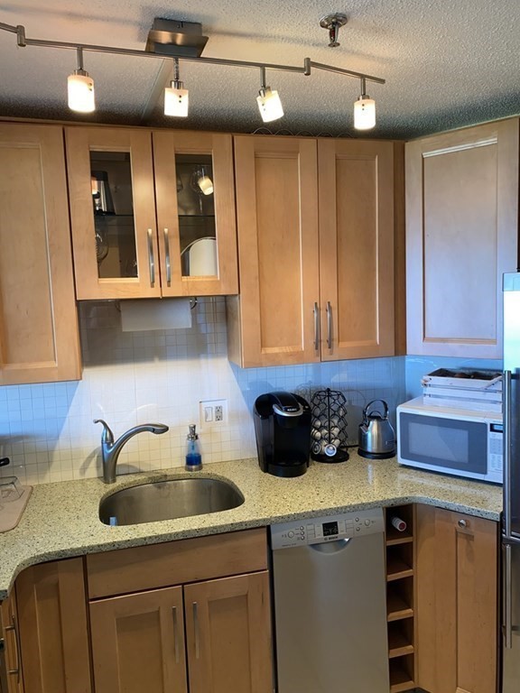 133 Commander Shea Boulevard, Unit 711 Quincy, MA 02171 - Photo 5 of 21 a kitchen with stainless steel appliances a sink cabinets and wooden floor