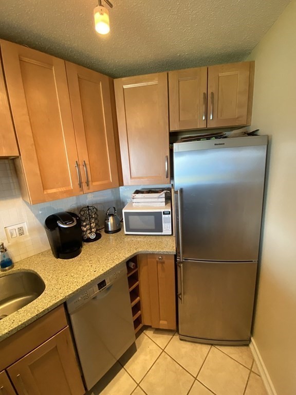 133 Commander Shea Boulevard, Unit 711 Quincy, MA 02171 - Photo 6 of 21 a kitchen with a refrigerator sink and cabinets