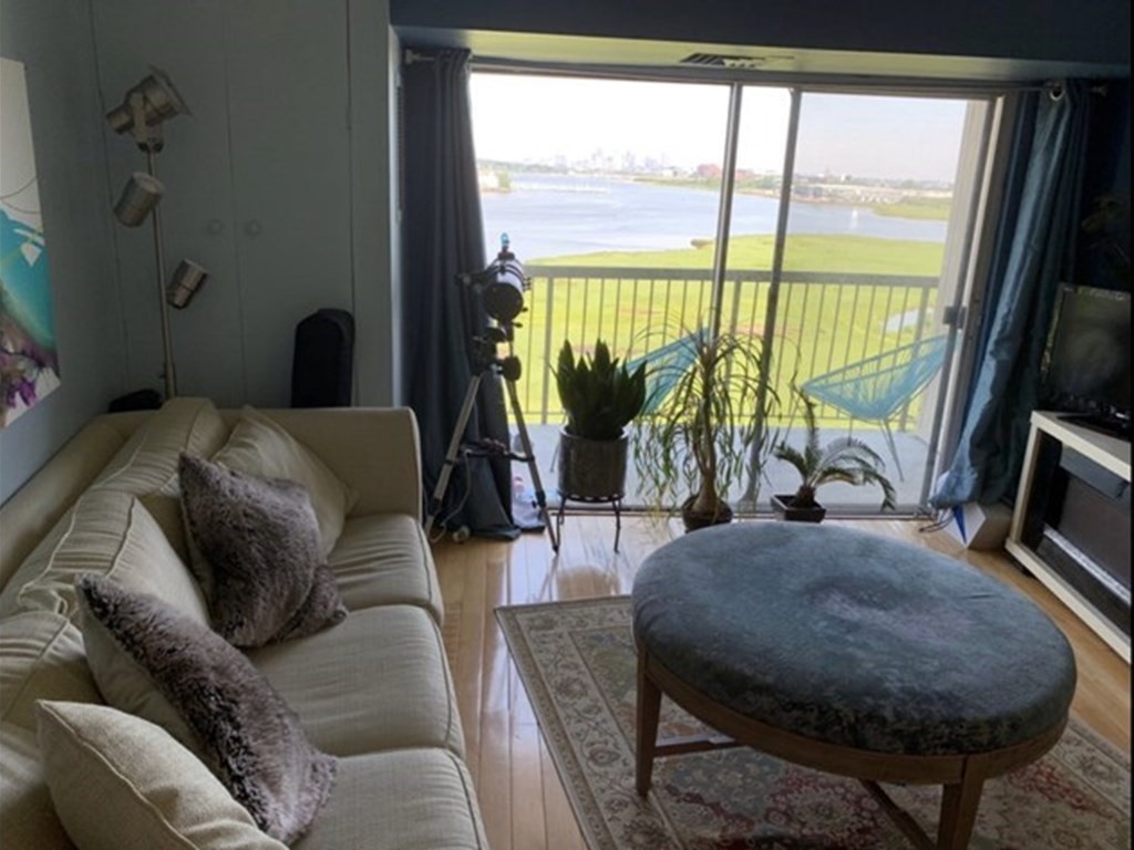 133 Commander Shea Boulevard, Unit 711 Quincy, MA 02171 - Photo 9 of 21 a living room with furniture a flat screen tv and a floor to ceiling window