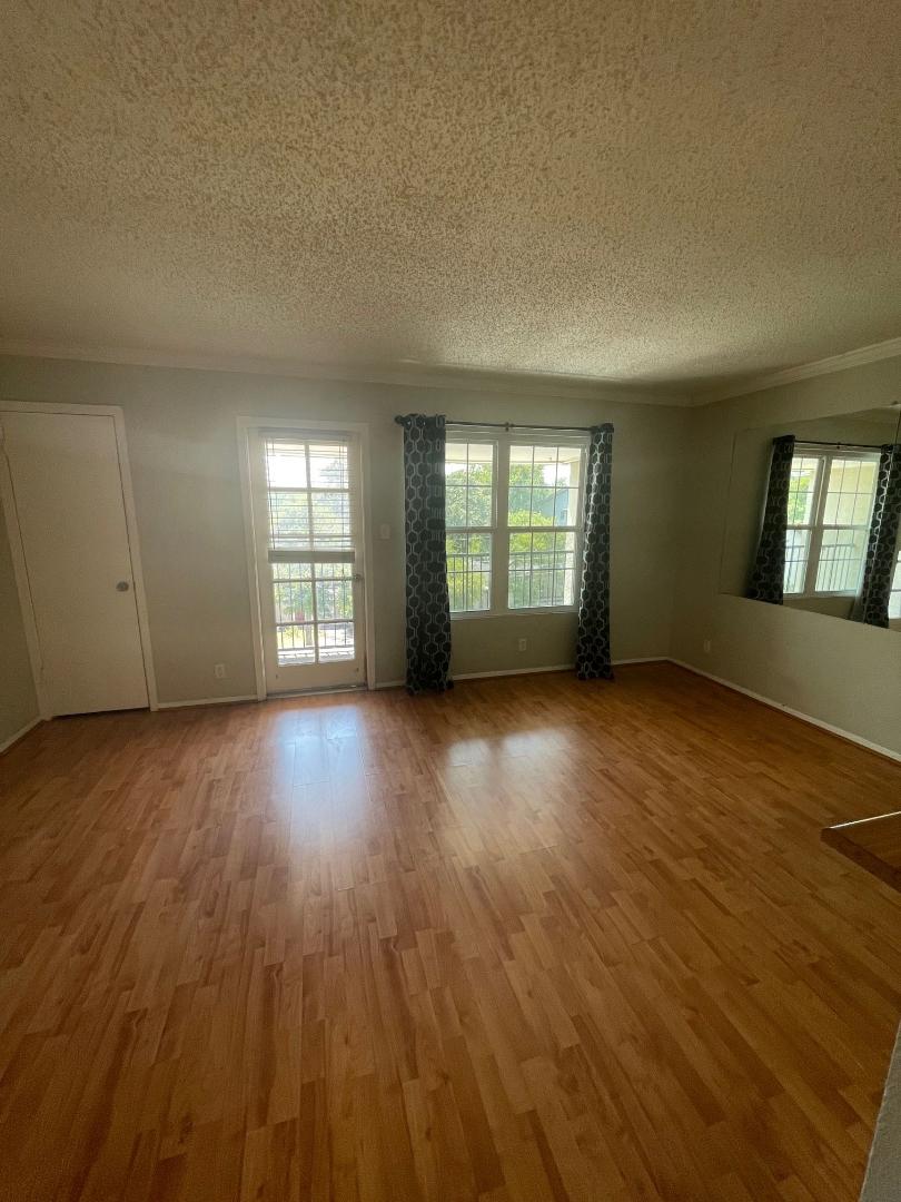 910 Duncan Lane, Unit 44 Austin, TX 78705 - Photo 9 of 15 Natural light illuminates this spacious area, highlighting the rich hardwood flooring and outdoor access.