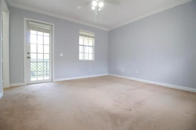 an empty room with windows and chandelier fan