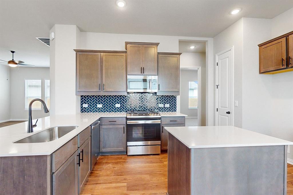 4907 Escape Rivera Drive Austin, TX 78747 - Photo 4 of 28 A contemporary kitchen features rich wooden flooring, pristine countertops, and modern appliances.