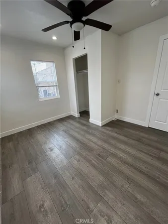 an empty room with wooden floor chandelier and windows