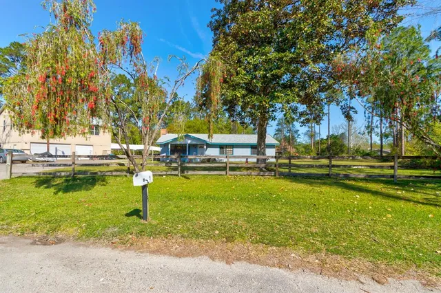 a view of a house with a big yard and large tree