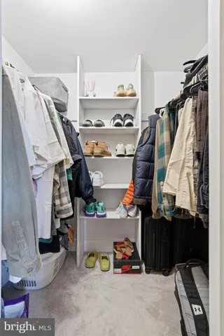 a view of walk in closet with clothes and shoes