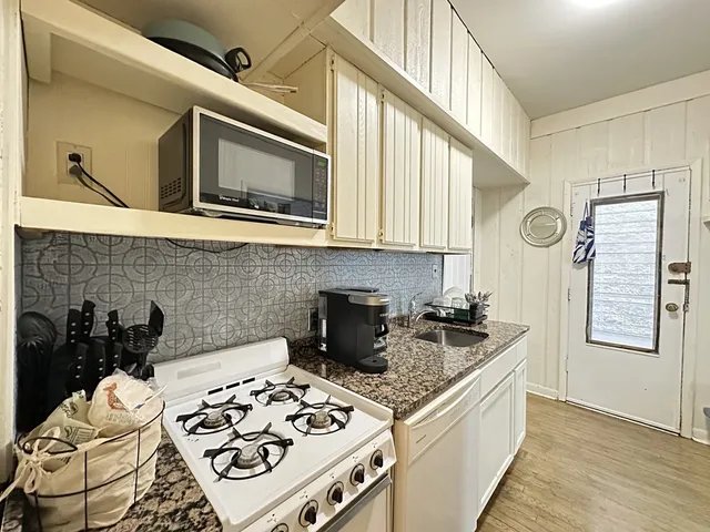 a kitchen with stainless steel appliances granite countertop a stove a sink and a microwave