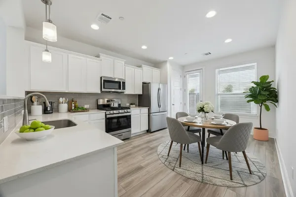 a kitchen with a dining table chairs and refrigerator