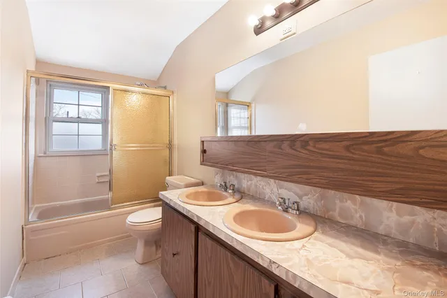 a bathroom with a granite countertop sink a toilet a mirror and shower