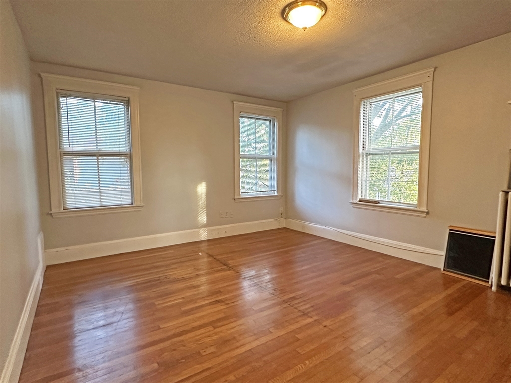 399 Newtonville Avenue, Unit 2 Newton, MA 02460 - Photo 12 of 24 a view of an empty room with wooden floor and windows