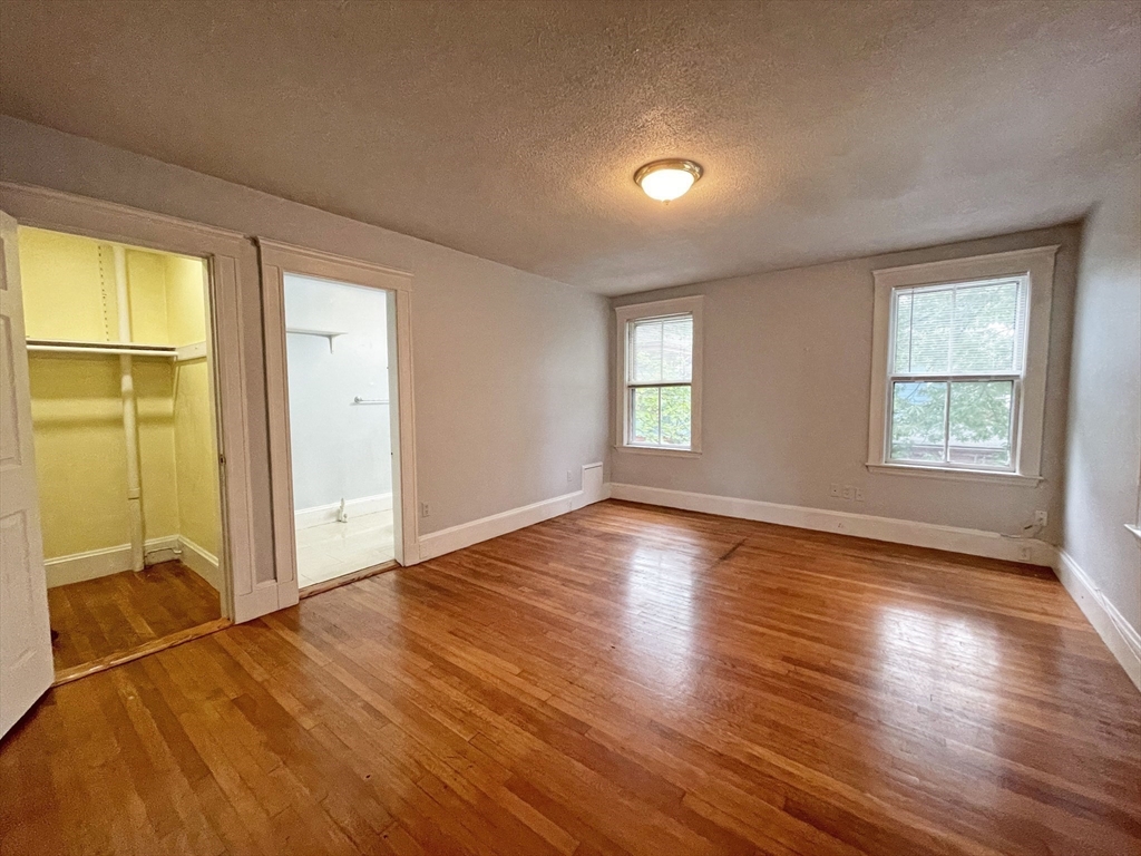 399 Newtonville Avenue, Unit 2 Newton, MA 02460 - Photo 14 of 24 an empty room with wooden floor and windows