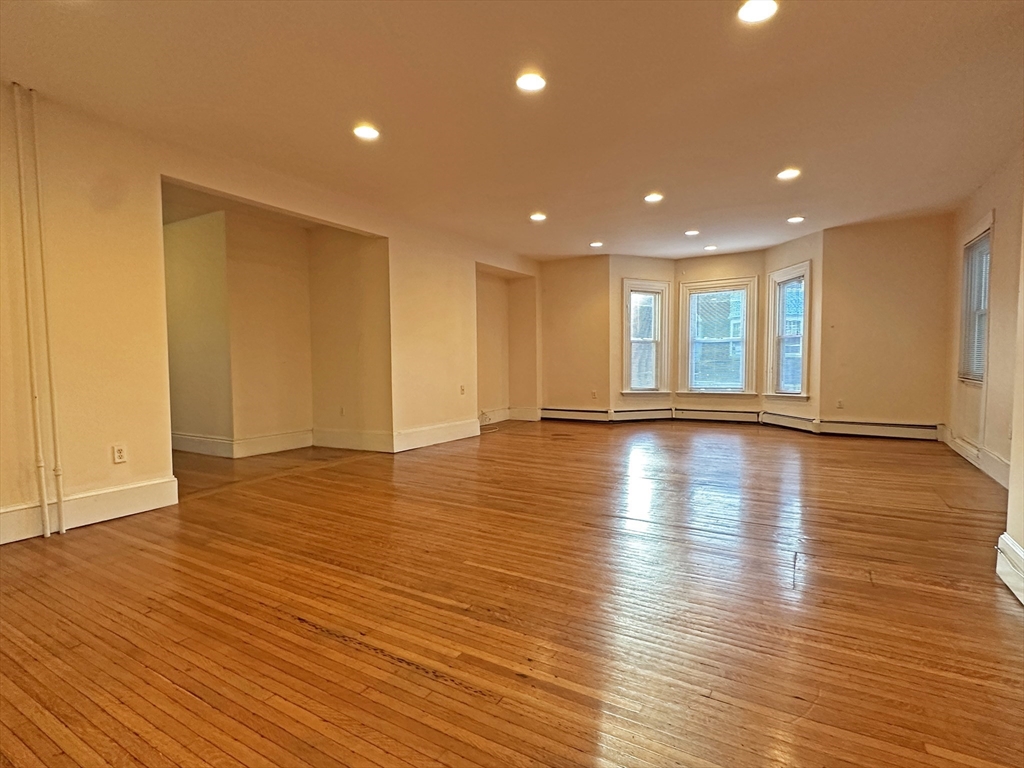 399 Newtonville Avenue, Unit 2 Newton, MA 02460 - Photo 3 of 24 a view of an empty room with wooden floor and a window
