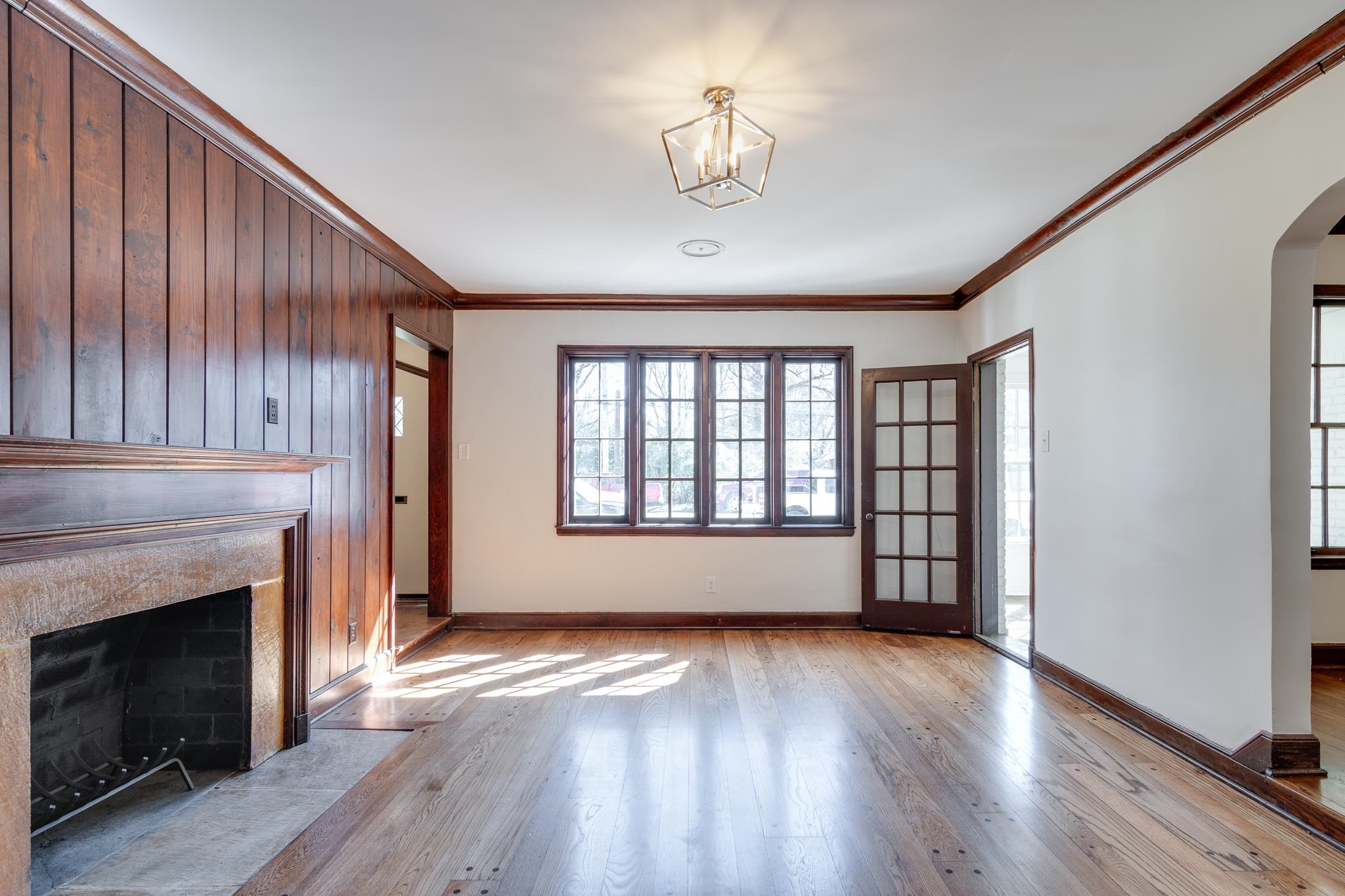 Living room with charming wood panel and peg hardwood flooring, entry to the sun/office is visible in this photo