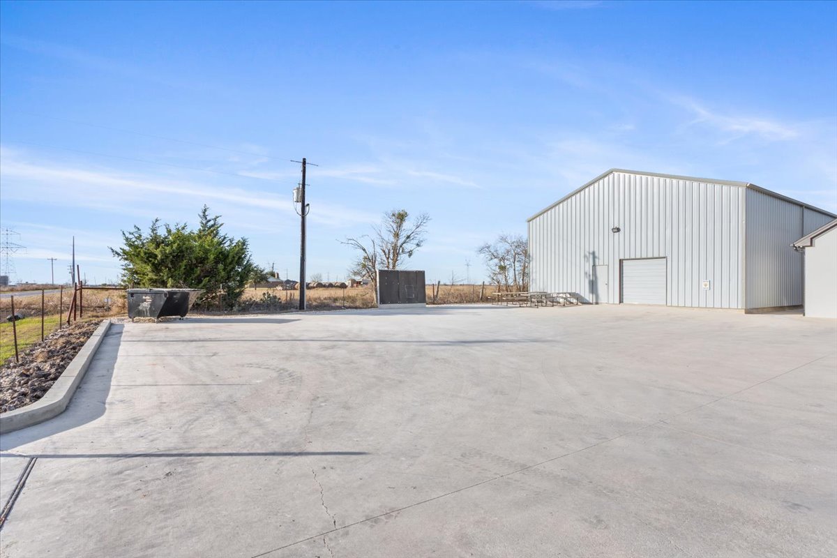 10940 Wedel Cemetery Road Rogers, TX 76569 - Photo 27 of 31 A spacious concrete lot fronts this practical and versatile metal building, ideal for various business needs.