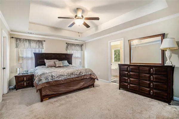 a bed sitting in a bedroom next to a window and a chandelier