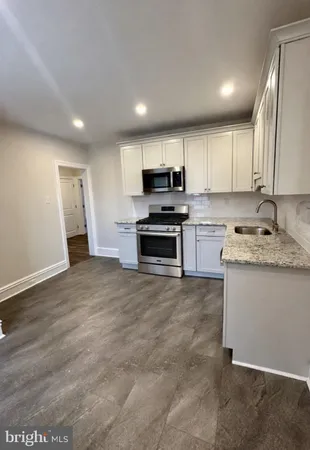 a kitchen with kitchen island granite countertop a stove top oven a sink a counter space and cabinets