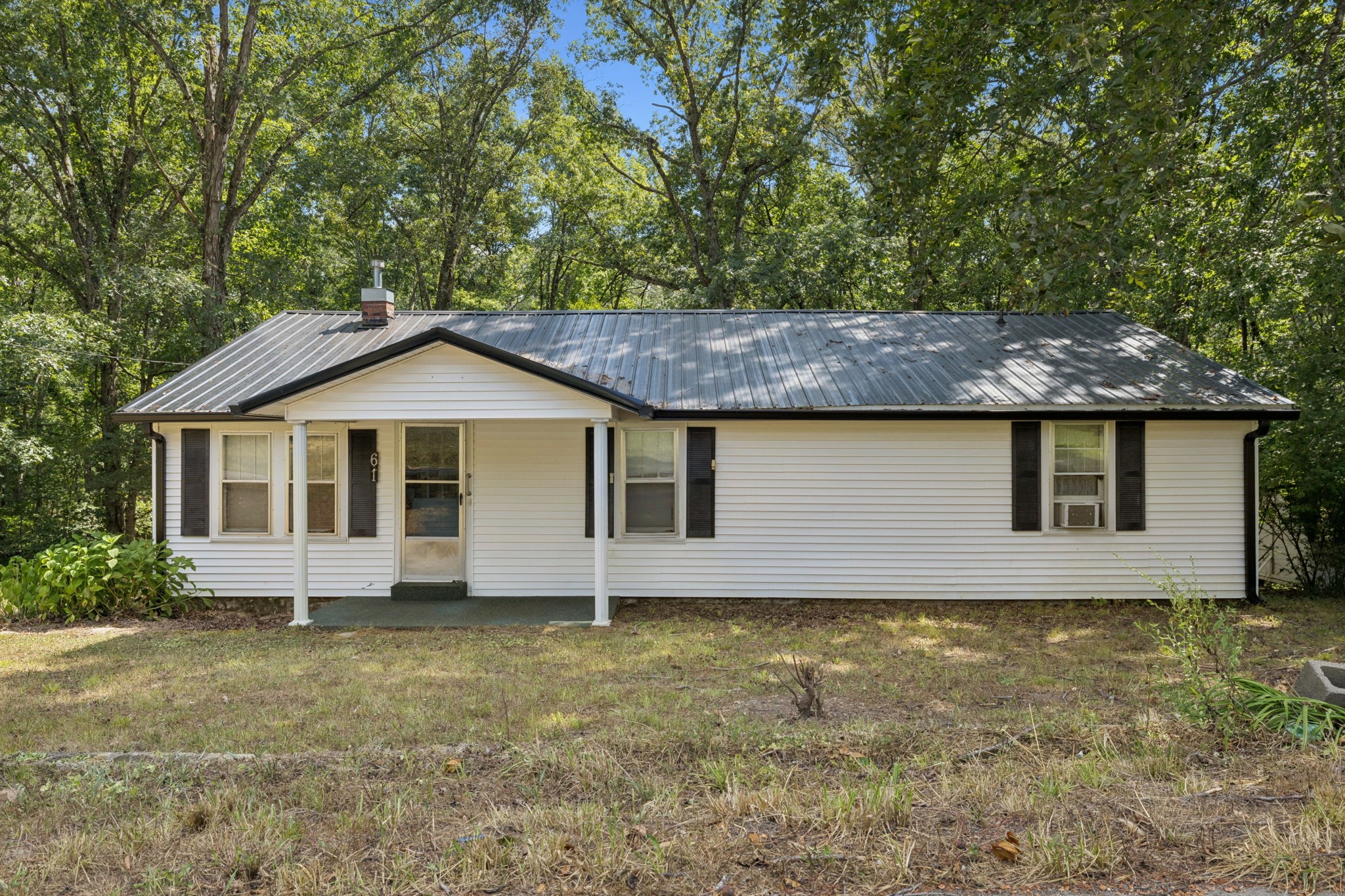 a front view of house with yard and trees in the background