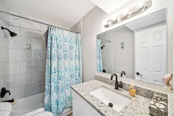 a bathroom with a granite countertop sink a mirror and shower