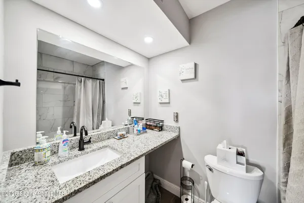 a bathroom with a granite countertop sink mirror and a toilet