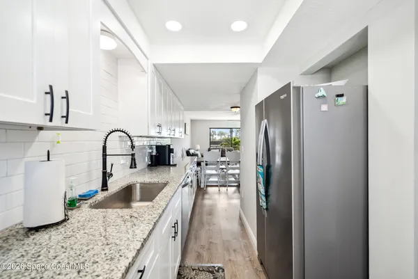 a kitchen with stainless steel appliances granite countertop a refrigerator a stove and a sink with living area