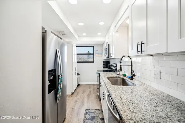 a kitchen with stainless steel appliances granite countertop a sink refrigerator and cabinets