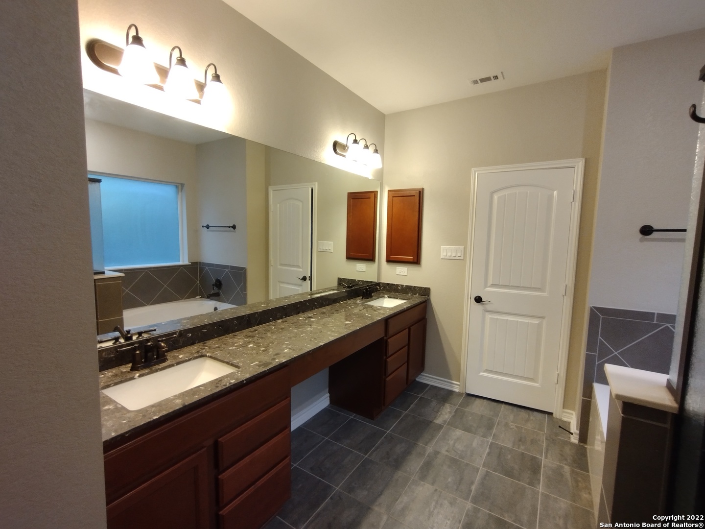 11212 Hill Top Loop Helotes, TX 78023 - Photo 17 of 34 a spacious bathroom with a granite countertop sink and a mirror
