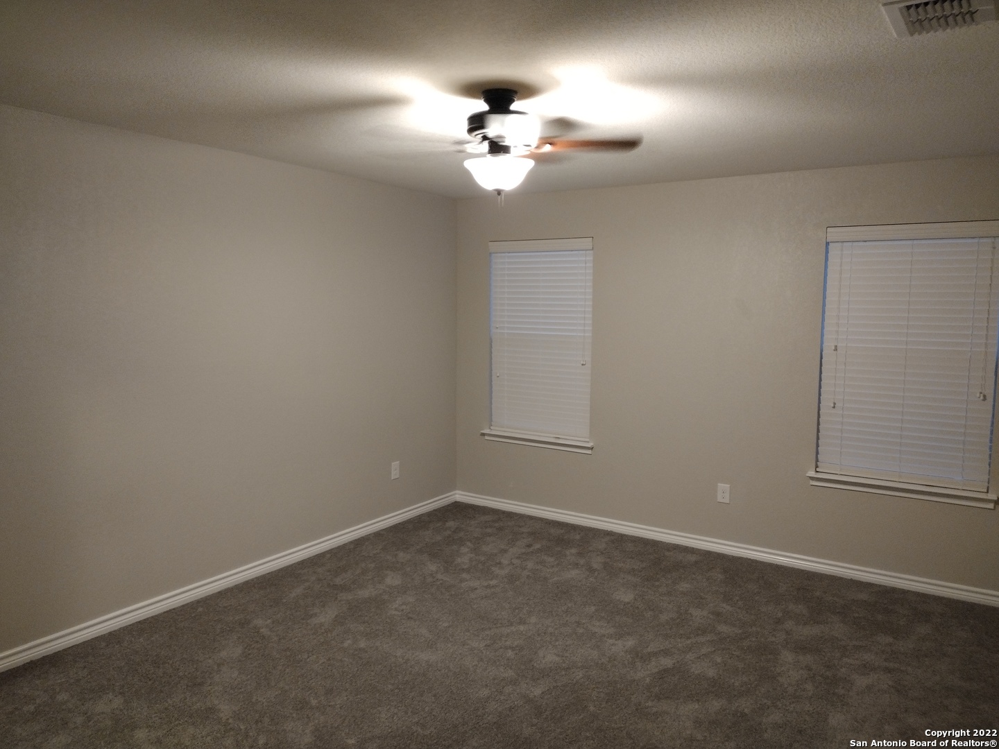 11212 Hill Top Loop Helotes, TX 78023 - Photo 26 of 34 an empty room with a chandelier fan and windows