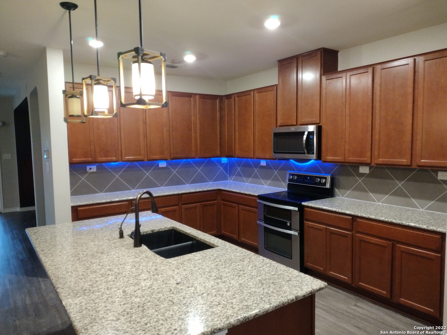11212 Hill Top Loop Helotes, TX 78023 - Photo 10 of 34 a kitchen with stainless steel appliances granite countertop a sink a stove and a wooden floors