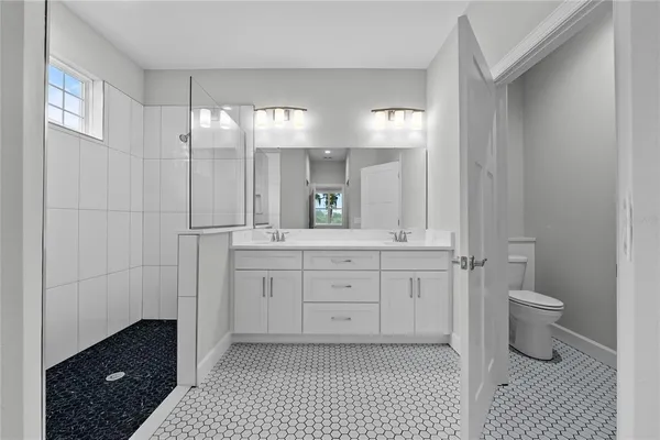 a spacious bathroom with a double vanity sink a mirror and a toilet